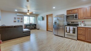 A spacious living area with a large sofa, a dining table with chairs, a kitchen with modern appliances, and wooden cabinets. - Tucson Home ~ 8 Mi to Saguaro National Park (Tucson)