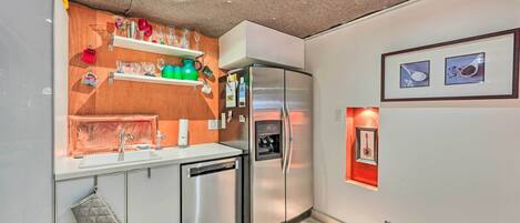 A modern kitchen with a built-in dishwasher, a refrigerator, and a countertop with various kitchen items.