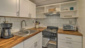 A kitchen with white cabinets, a wooden countertop, a coffee maker, a sink, a stove, and a toaster. - Guest Cottage on 1 Acre: 20 Mins to Asheville! (Black Mountain)