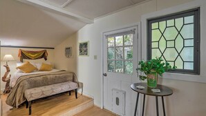 A bedroom with a bed, bench, lamp, and a window with a geometric pattern. - Guest Cottage on 1 Acre: 20 Mins to Asheville! (Black Mountain)