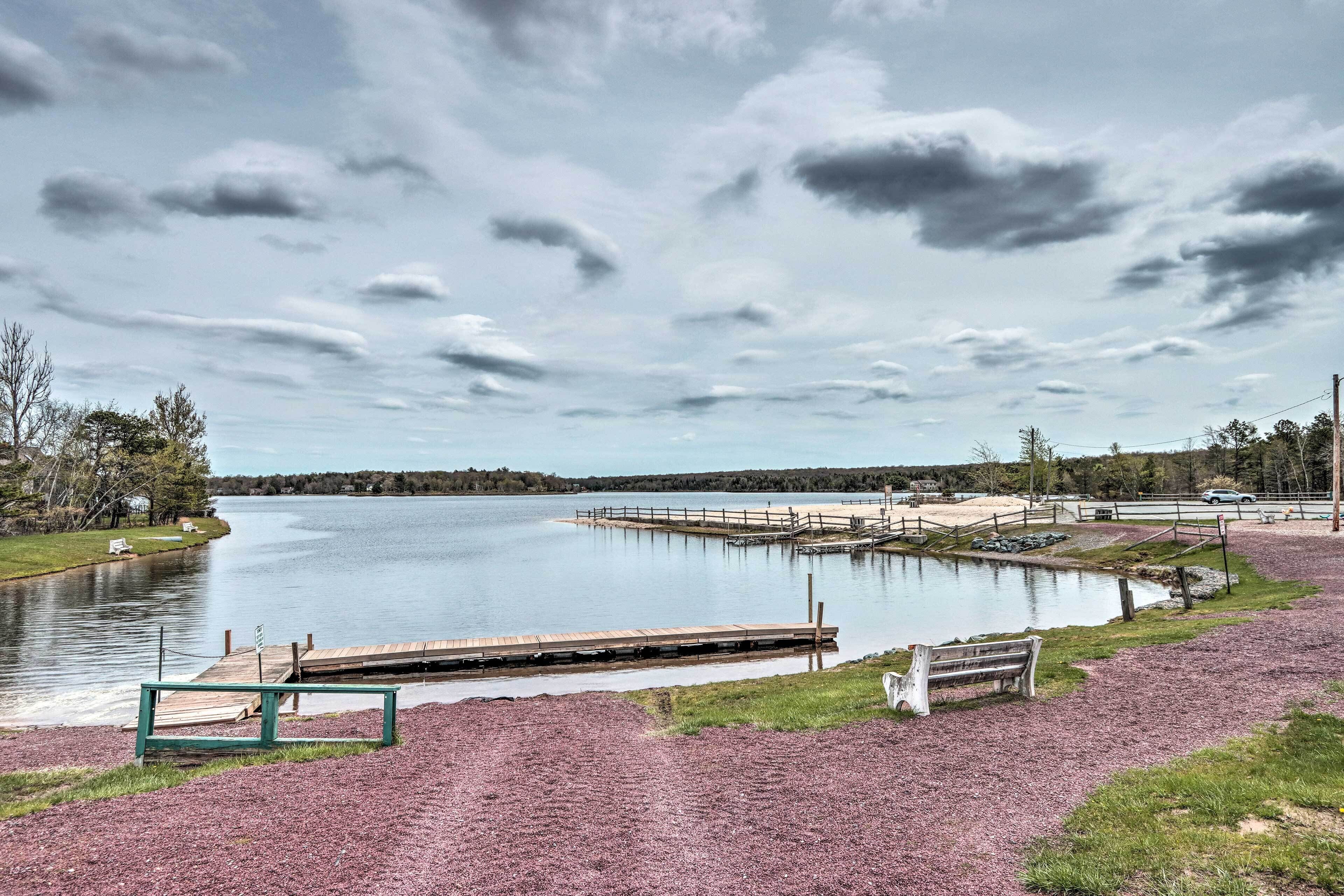 A lakeside park with a wooden dock, a bench, and a gravel path.
