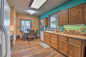 A kitchen with wooden cabinets, a granite countertop, and a dining area with chairs and a table. - Shared Backyard & Hot Tub: Restful Mesa Retreat! (Mesa)