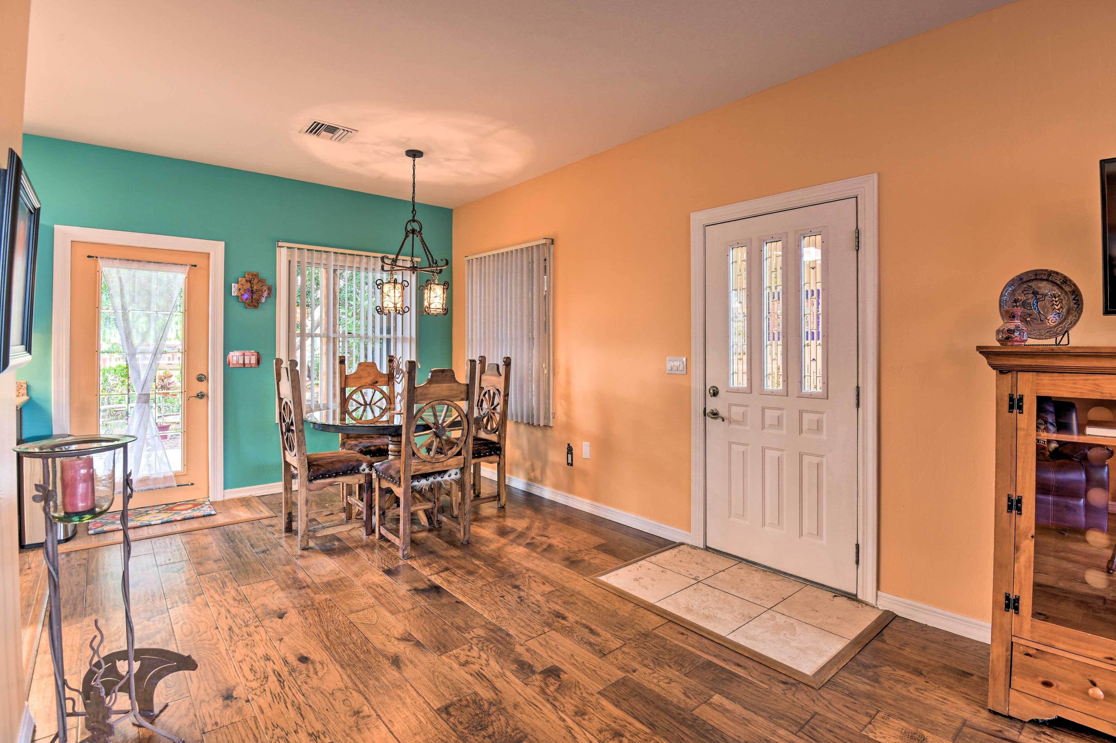 A dining area with a wooden table and chairs, a chandelier, and a door with a glass panel.