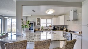A modern kitchen with a central island, wicker chairs, and built-in cabinets. - Bright Ormond Beach Home ~ 14 Mi to Daytona! (Ormond Beach)