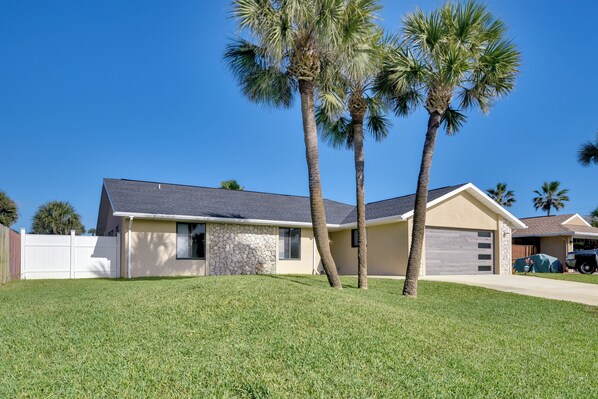 A single-story house with a stone facade, a garage, and a well-maintained lawn with two palm trees. - Bright Ormond Beach Home ~ 14 Mi to Daytona! (Ormond Beach)