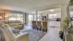 A spacious living area with a sofa, chairs, and a kitchen in the background. - Bright Ormond Beach Home ~ 14 Mi to Daytona! (Ormond Beach)