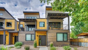 A modern multi-story residential building with a mix of wood and metal exterior, a central entrance, and a small front garden. - Sleek & Modern Townhome, 3 Blocks to Main St! (Moab)