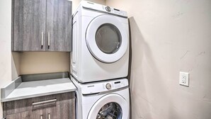 A laundry area with a stacked washer and dryer, a wooden cabinet, and a countertop. - Sleek & Modern Townhome, 3 Blocks to Main St! (Moab)