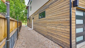 A building with a wooden exterior wall, a gravel pathway, and a metal fence. - Sleek & Modern Townhome, 3 Blocks to Main St! (Moab)