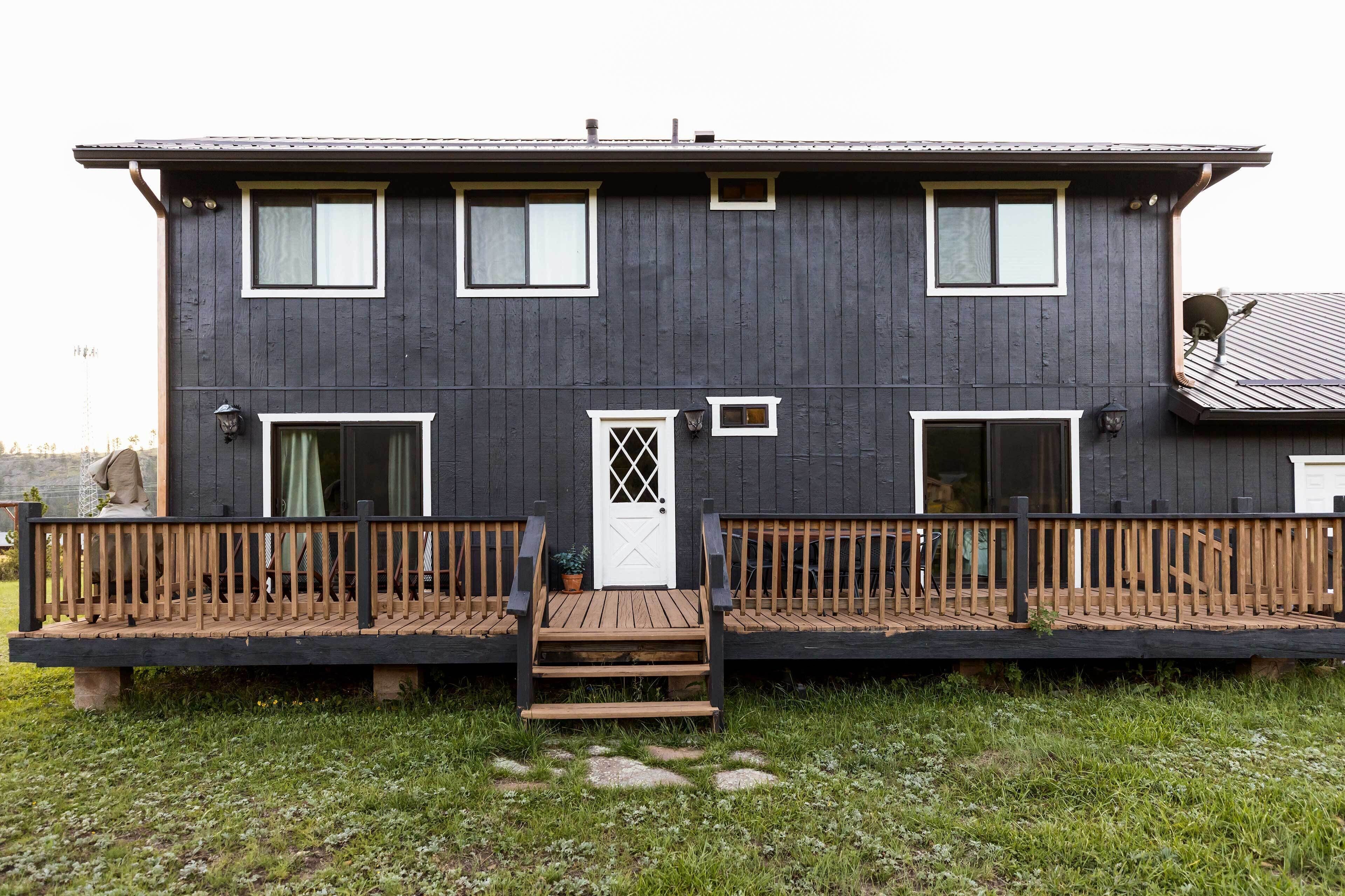 Un bâtiment à deux étages doté d’une terrasse en bois, d’une porte blanche et de nombreuses fenêtres.
