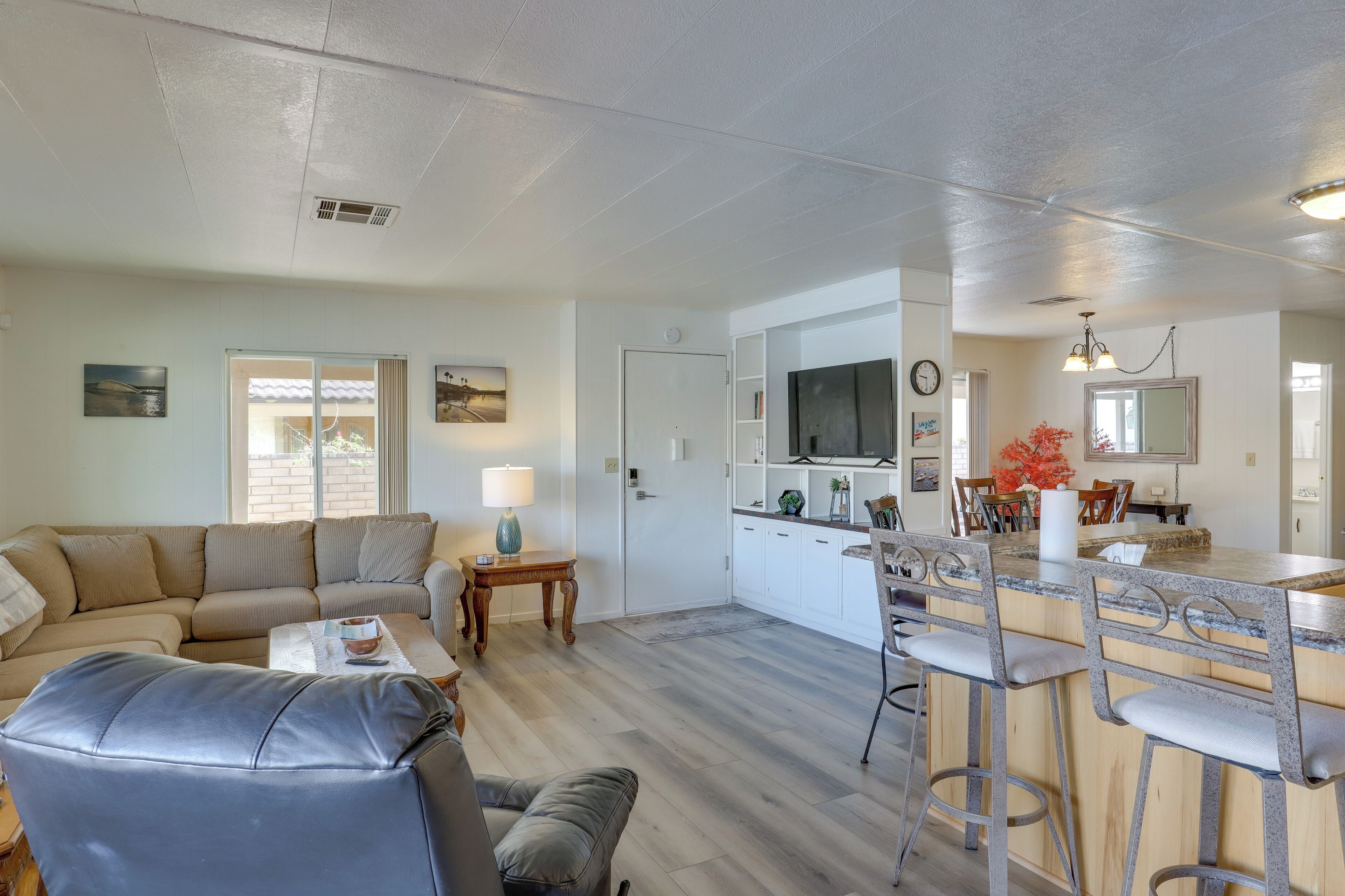 Un salon comprenant un canapé, une table basse et un coin repas avec un bar.