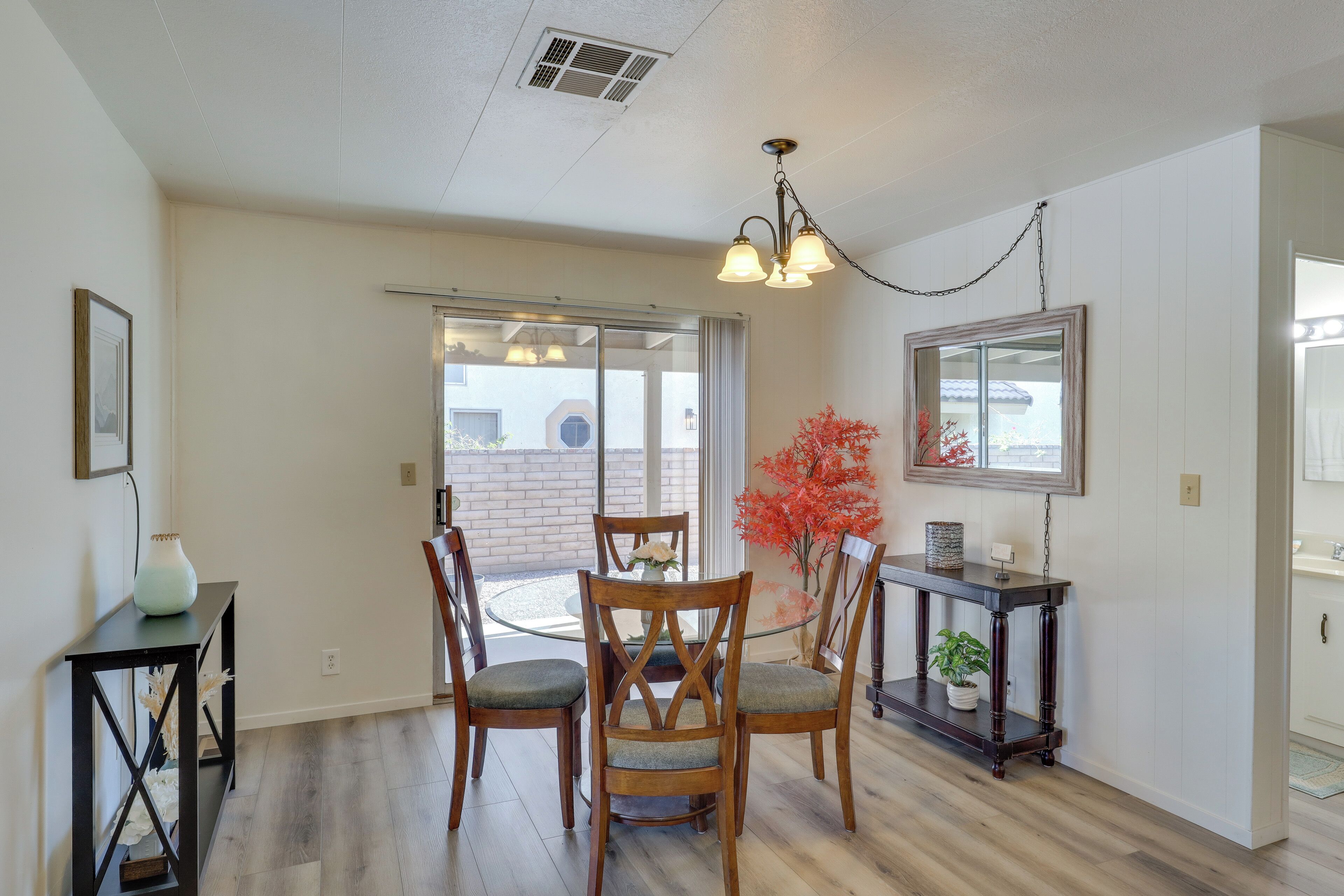 A dining area with a round table, wooden chairs, a vase, and a potted plant.