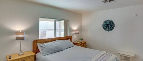 A bedroom with a bed, wooden nightstands, a bedside table, a wall decoration, and a window.