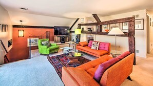 A cozy living room with a green armchair, orange sofa, and a coffee table. - Creek Access & Deck: Runningwater Lancaster Gem (Lancaster)