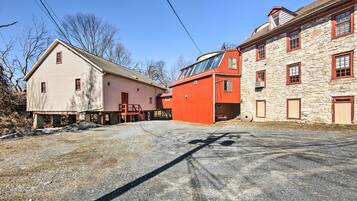 Un edificio con fachada de piedra y ventanas rojas, un edificio rojo con techo plano y un edificio color beige con techo a dos aguas.
