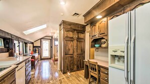 A kitchen with wooden cabinets, a refrigerator, and a dining area with a table and chairs. - Creek Access & Deck: Runningwater Lancaster Gem (Lancaster)