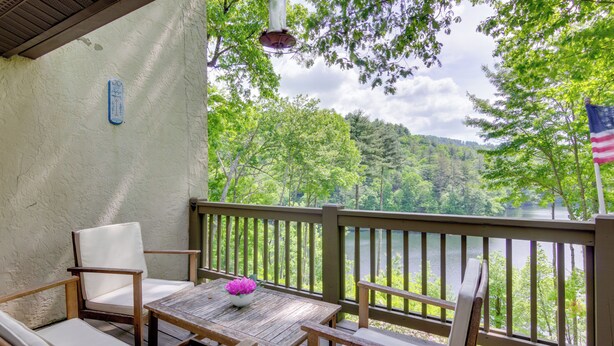 A wooden deck with a table and chairs, overlooking a lake and forested area. - High-end Sapphire Retreat on Fairfield Lake! (Sapphire)