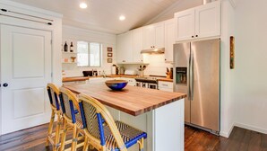 A kitchen with white cabinets, a wooden island, a stainless steel refrigerator, and wicker chairs. - High-end Sapphire Retreat on Fairfield Lake! (Sapphire)