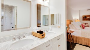 A hotel bathroom with two sinks, a large mirror, and a wooden bed with white bedding. - High-end Sapphire Retreat on Fairfield Lake! (Sapphire)