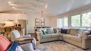 A spacious living room with a large sectional sofa, a dining area with a wooden table and chairs, and a kitchen with white cabinets and stainless steel appliances. - High-end Sapphire Retreat on Fairfield Lake! (Sapphire)