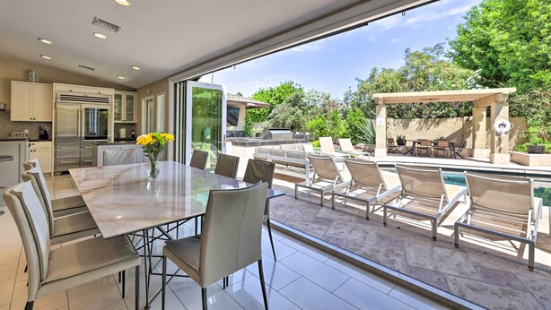 A modern kitchen with stainless steel appliances, a dining area with a marble table, and a patio with outdoor seating and a pool. - Outdoor Kitchen: Desert Dream Home in Scottsdale! (Scottsdale)