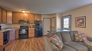 A compact kitchen with wooden cabinets, a microwave, a refrigerator, and a built-in oven. - Cozy Cedar Rapids Pad - 2 Blocks to Mercy Care! (Cedar Rapids)