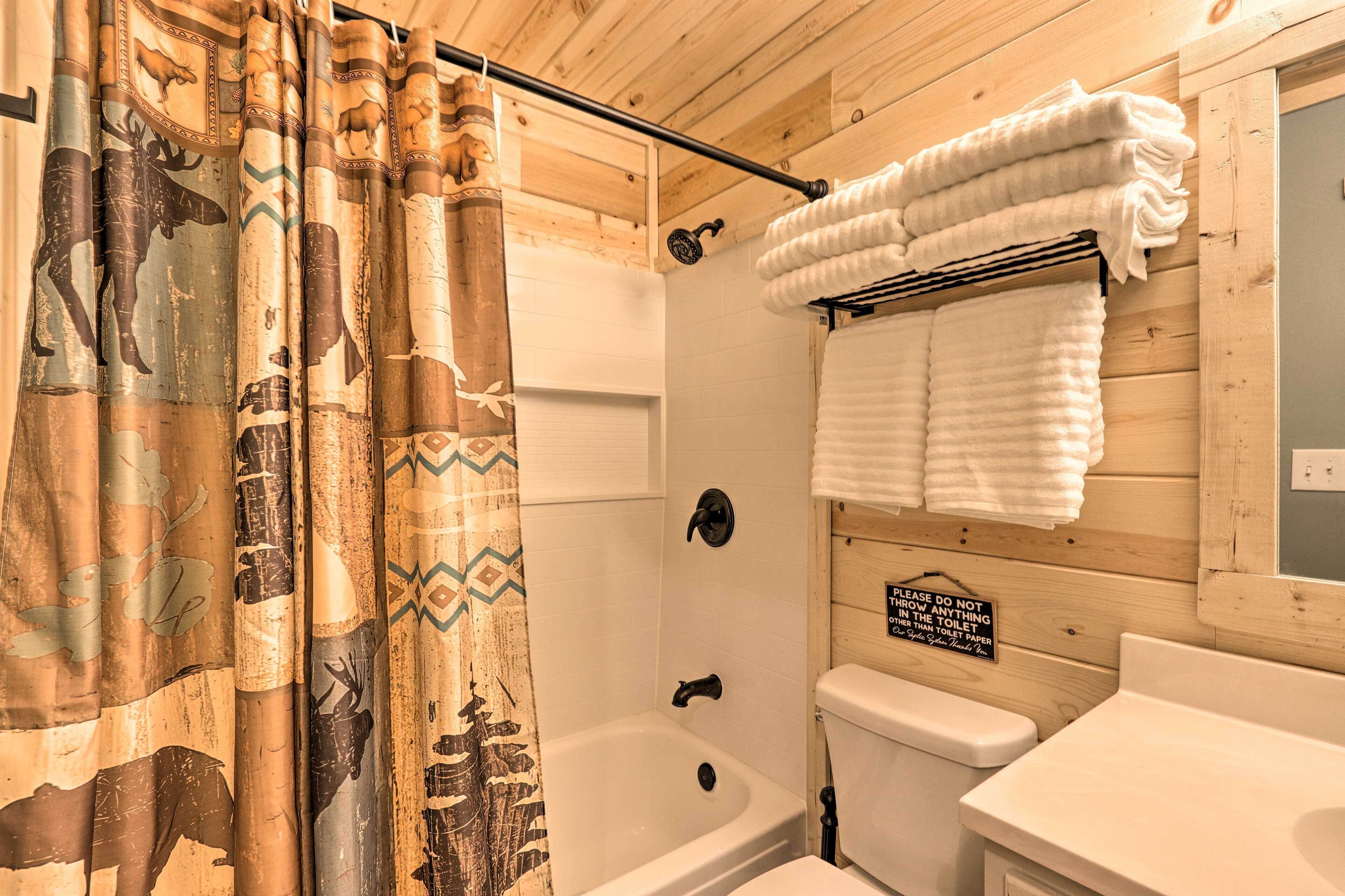 A bathroom with a shower curtain featuring animal prints, a bathtub, a toilet, and a sink.