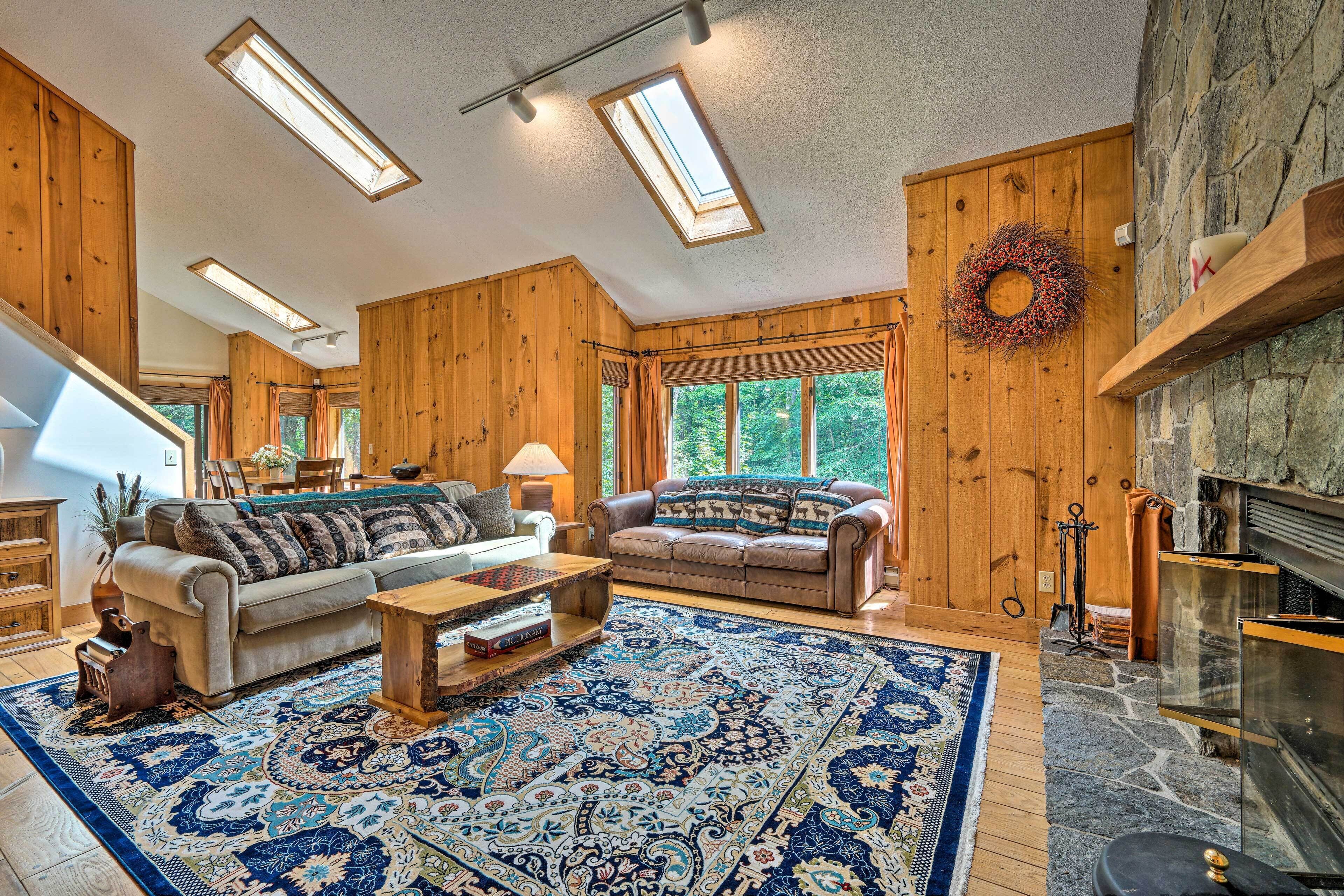 Ein geräumiges Wohnzimmer mit Holzwänden, einem Kamin und einem großen Teppich.