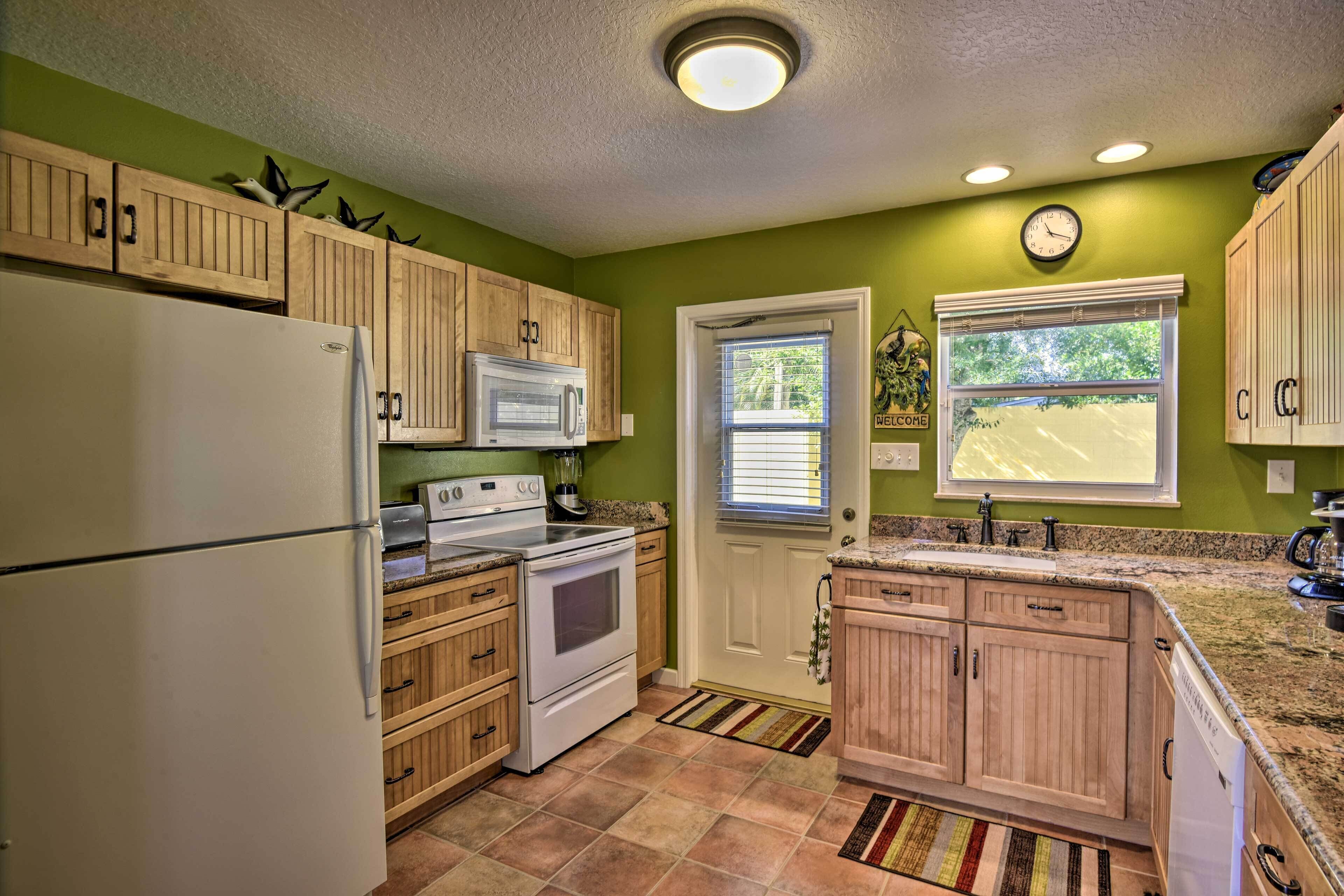 A kitchen with wooden cabinets, a white refrigerator, a microwave, an oven, a sink, and a window with blinds.