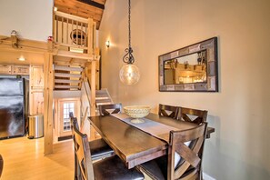A dining area with a wooden table, chairs, a hanging light fixture, and a mirror on the wall. - Updated Loon Townhome w/ Mtn Views & Ski Shuttle! (Lincoln)
