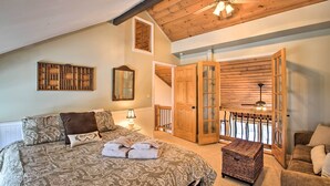 Ein Schlafzimmer mit einem großen Bett, einem Deckenventilator aus Holz, einer Holztür und Blick ins Freie.