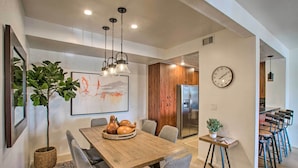 A modern dining area with a wooden table, grey chairs, and a chandelier. - Balconies & Resort Amenities: Scottsdale Condo (Scottsdale)