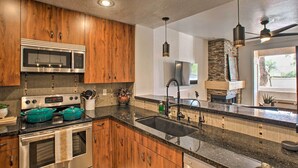 A modern kitchen with wooden cabinets, stainless steel appliances, a granite countertop, and a stone fireplace. - Balconies & Resort Amenities: Scottsdale Condo (Scottsdale)