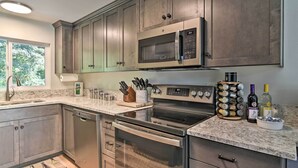 A modern kitchen with stainless steel appliances, wooden cabinets, and a granite countertop. - Waterfront Troutdale Hideaway: Sandy River Fishing (Troutdale)