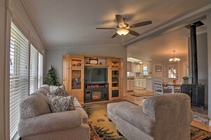 A living room with a fireplace, a ceiling fan, and a Christmas tree.