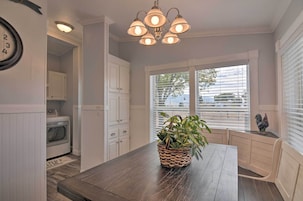 A kitchen with a wooden table, white cabinets, a built-in oven, and a window with blinds.