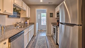 A kitchen with stainless steel appliances, granite countertops, and white cabinetry. - Modern Condo w/ Deck ~ 7 Mi To Branson Landing! (Branson)