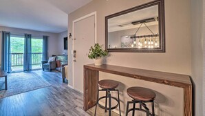 A modern living room with a wooden console table, two bar stools, a large mirror, and a potted plant. - Modern Condo w/ Deck ~ 7 Mi To Branson Landing! (Branson)