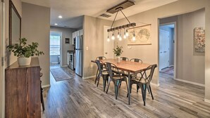A dining area with a wooden table and chairs, a hanging light fixture, and a potted plant. - Modern Condo w/ Deck ~ 7 Mi To Branson Landing! (Branson)