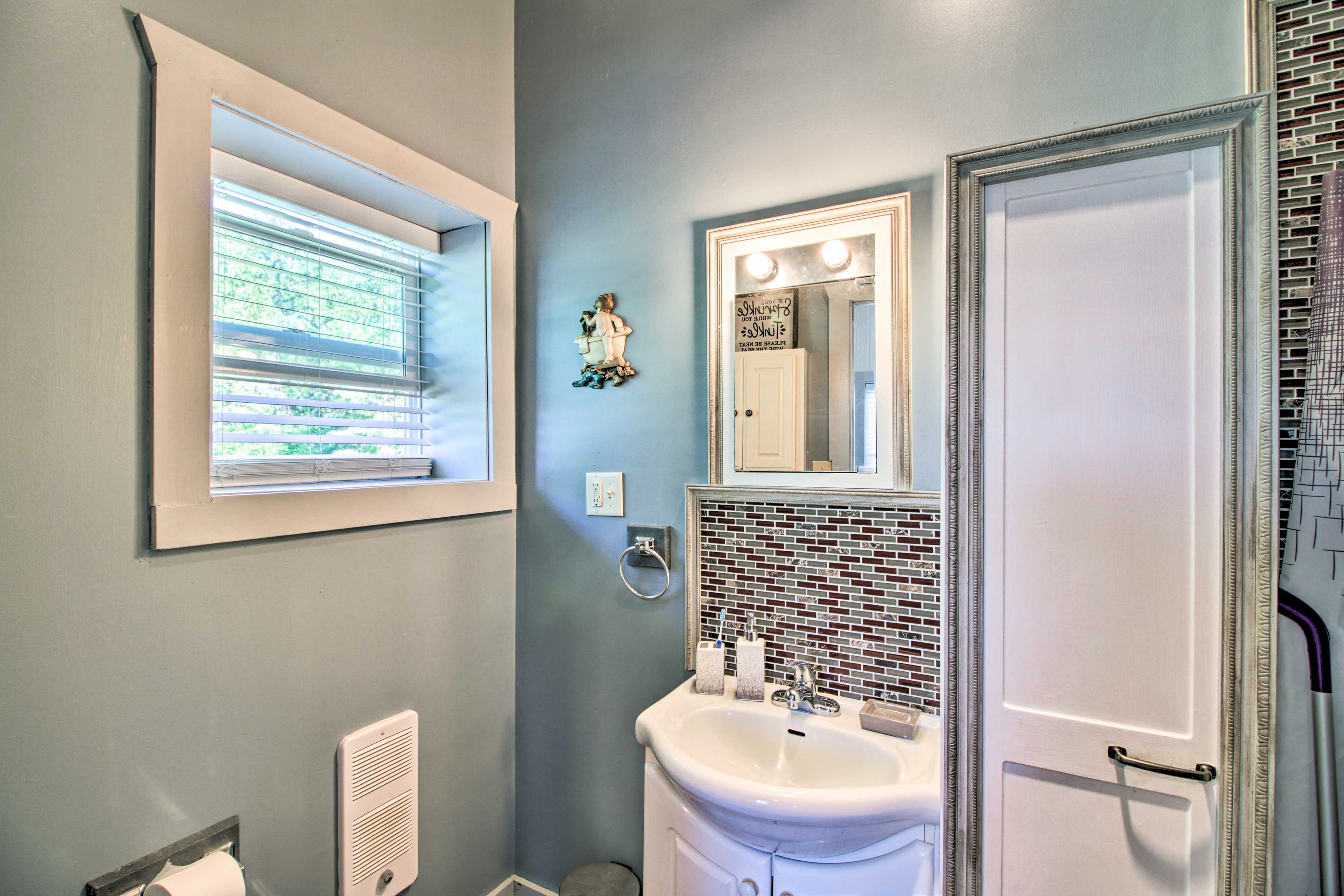 A bathroom with a window, a sink, a mirror, and a towel rack.