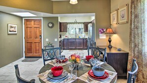 A dining area with a table set for four, a kitchen in the background, and a door leading outside. - Relaxing Green Valley Townhome ~ 30 Mi to Tucson! (Green Valley)