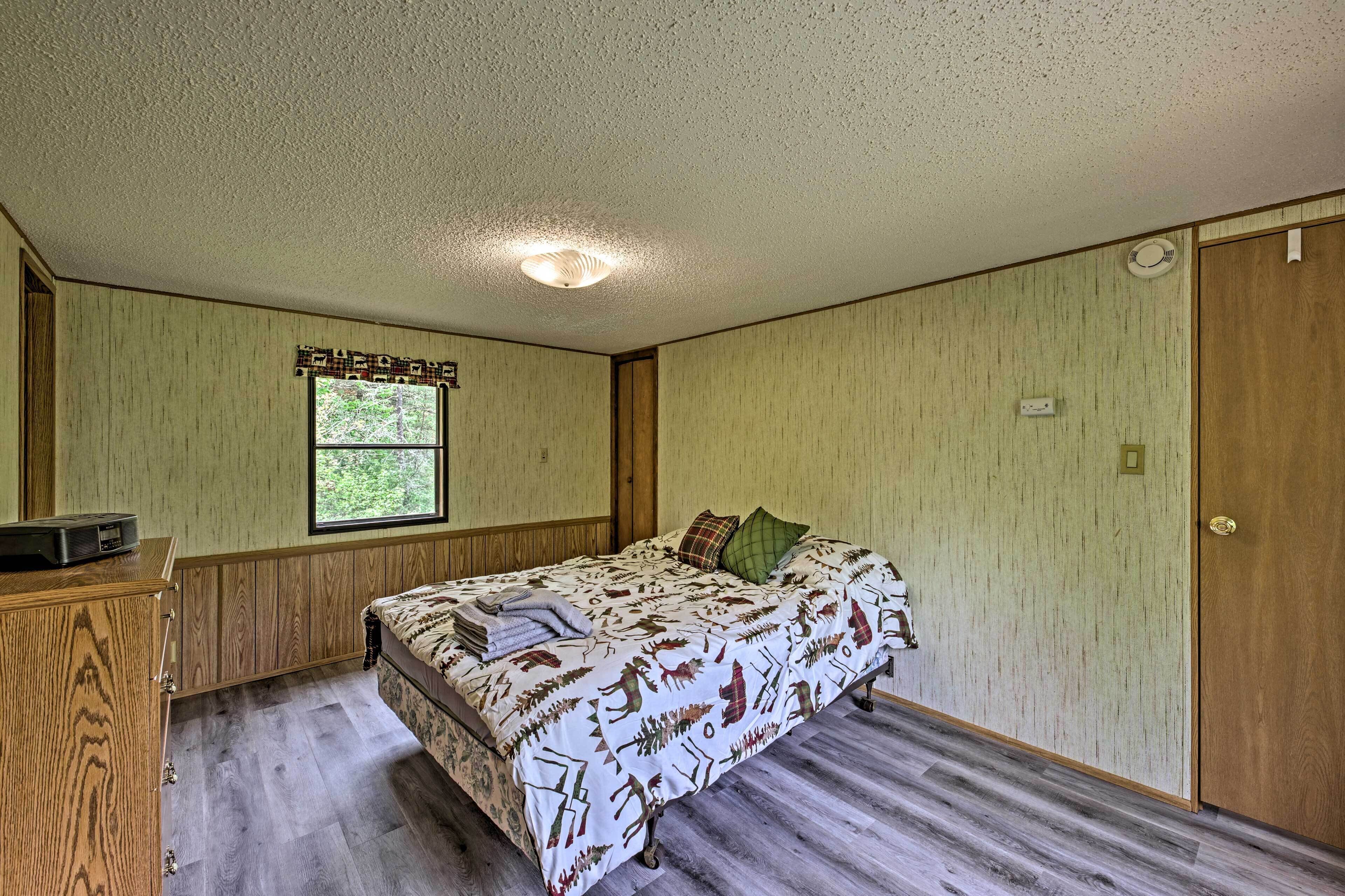 Una habitación con cama, ventana, cómoda de madera y puerta.