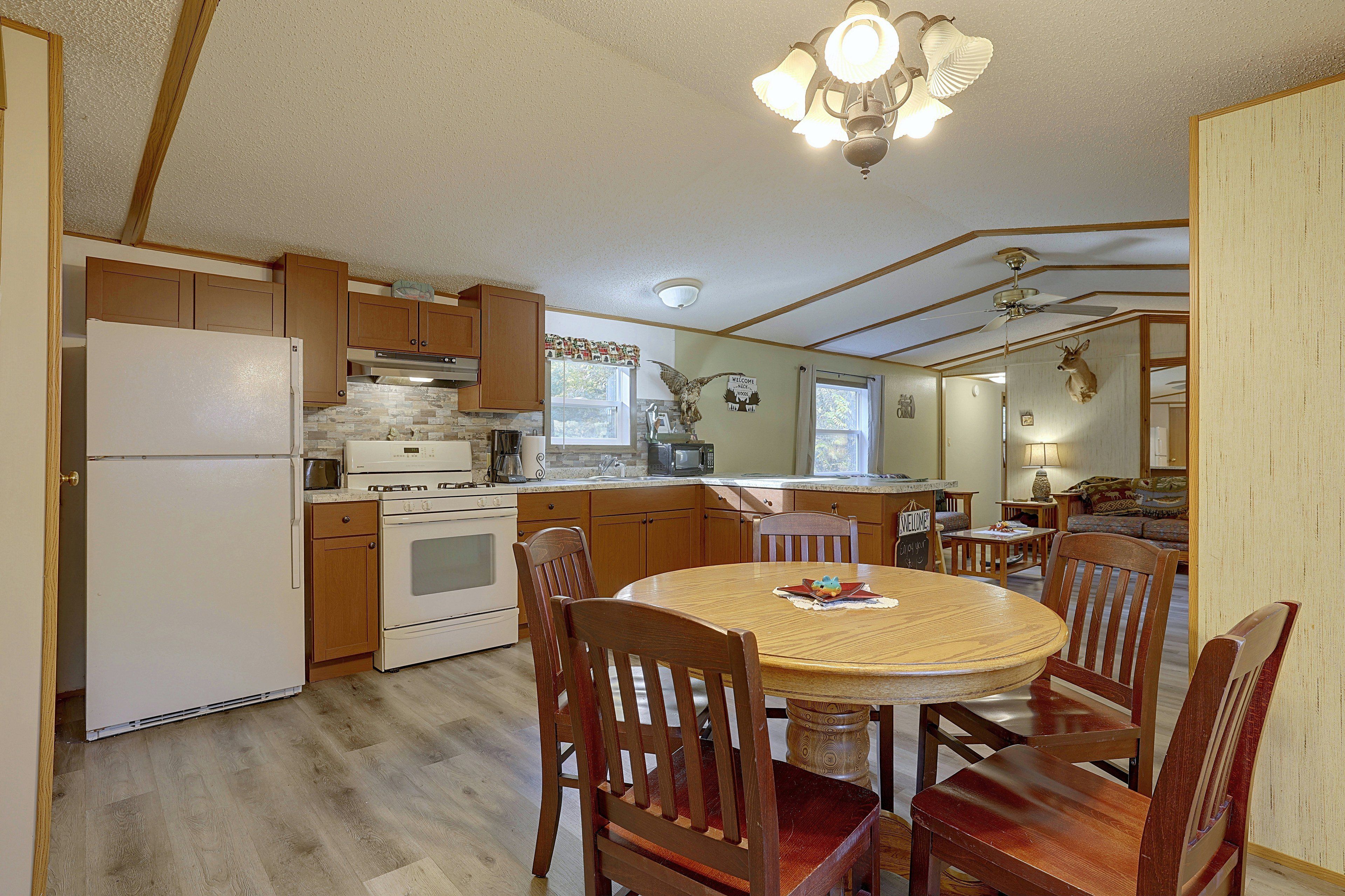 A kitchen with wooden cabinets, a stove, and a dining table with chairs.