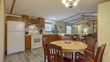 A kitchen with wooden cabinets, a stove, and a dining table with chairs.