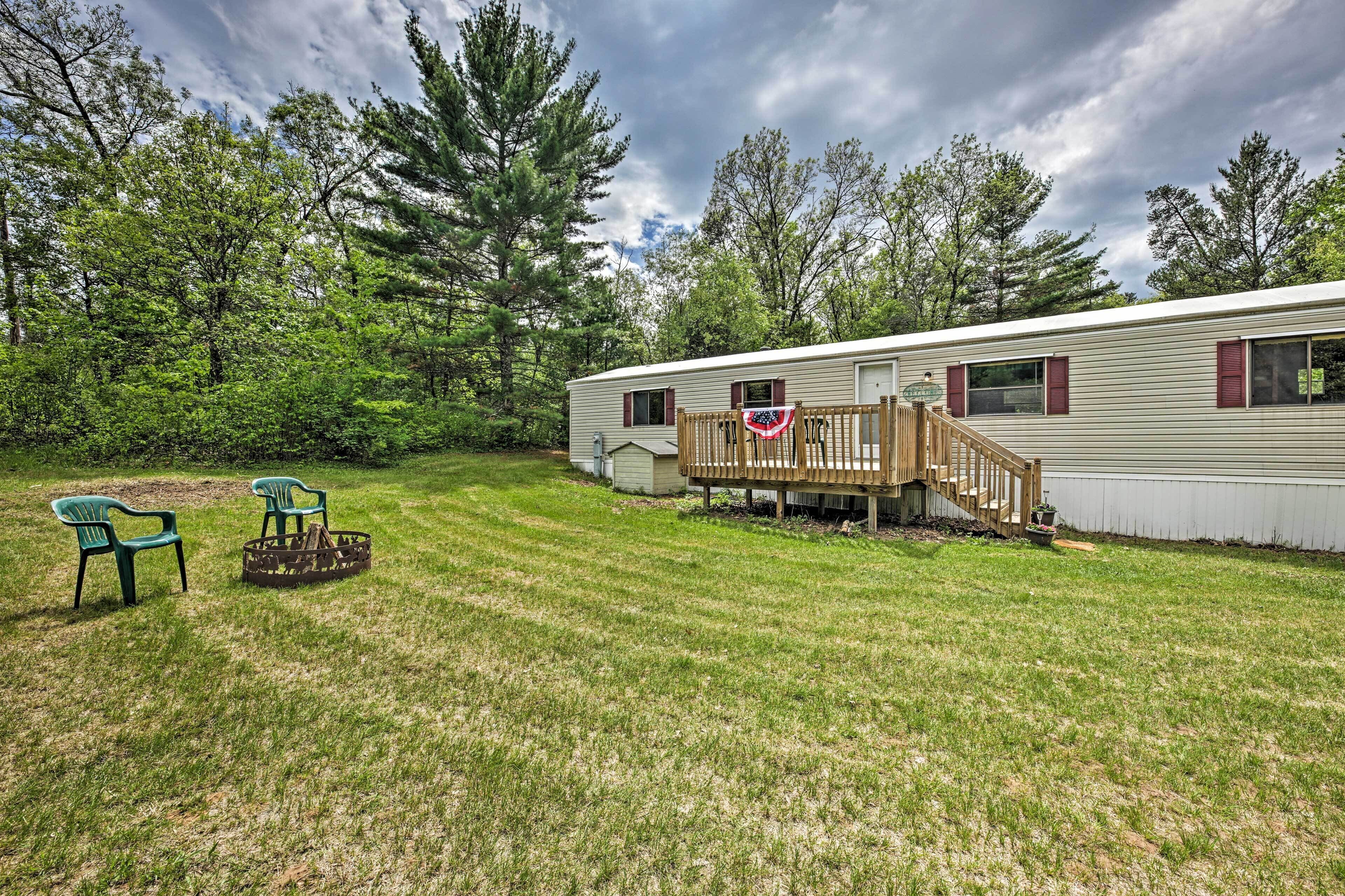 A mobile home with a wooden deck and a flag.