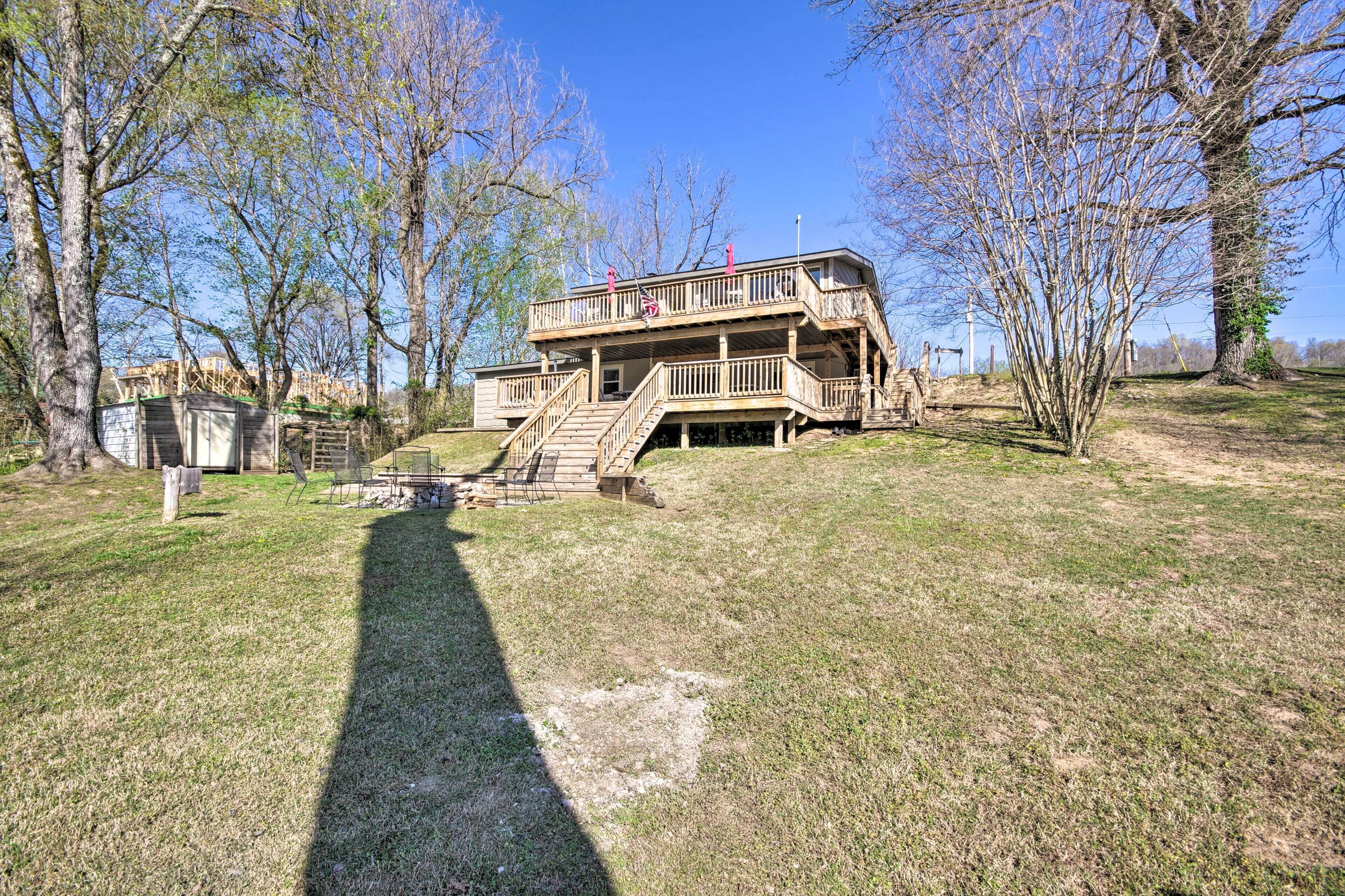 A two-story wooden cabin with a balcony, surrounded by trees and a grassy yard.