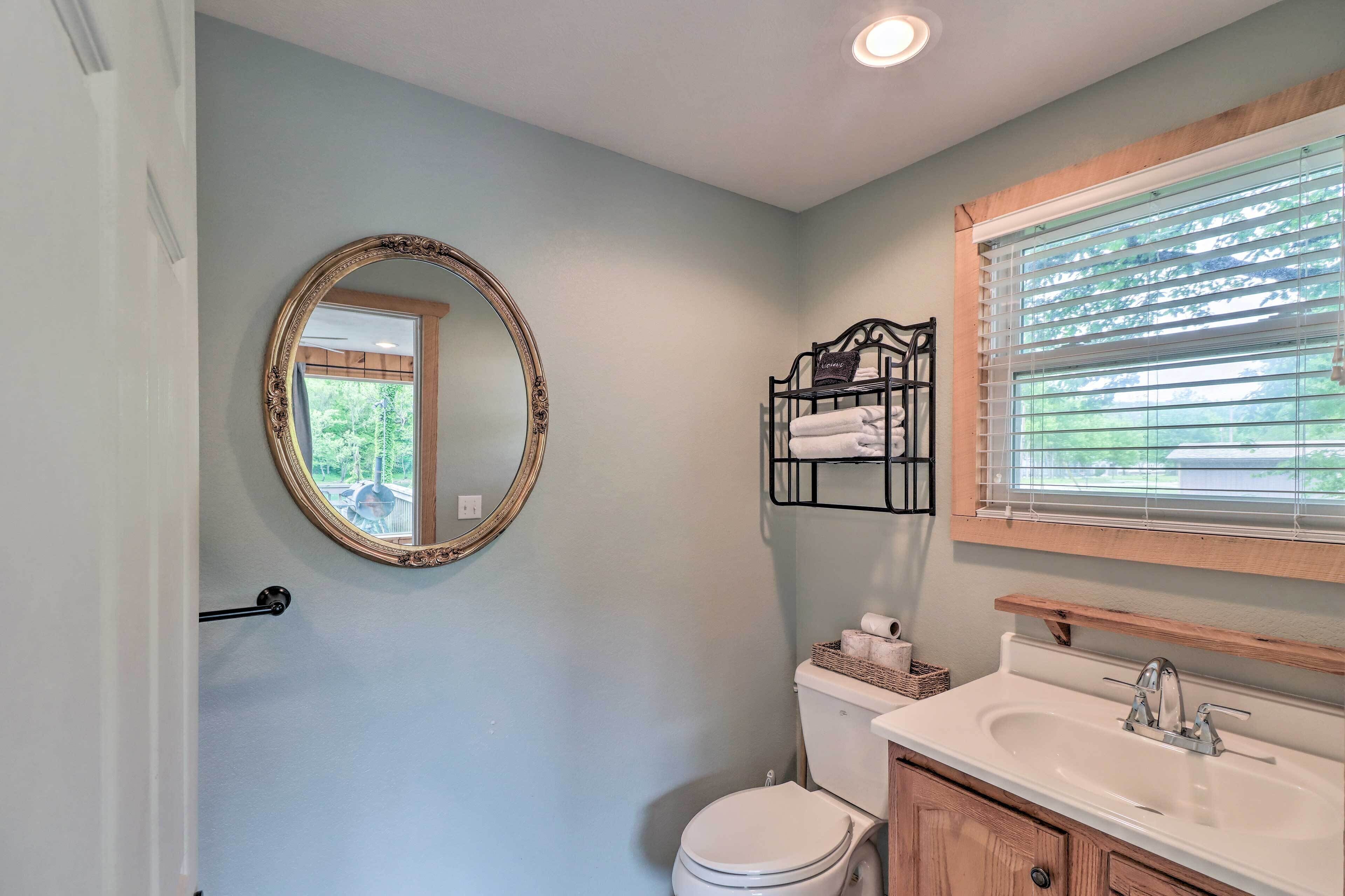 A bathroom with a toilet, sink, and mirror.