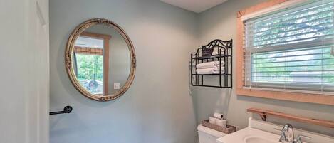 A bathroom with a toilet, sink, and mirror.