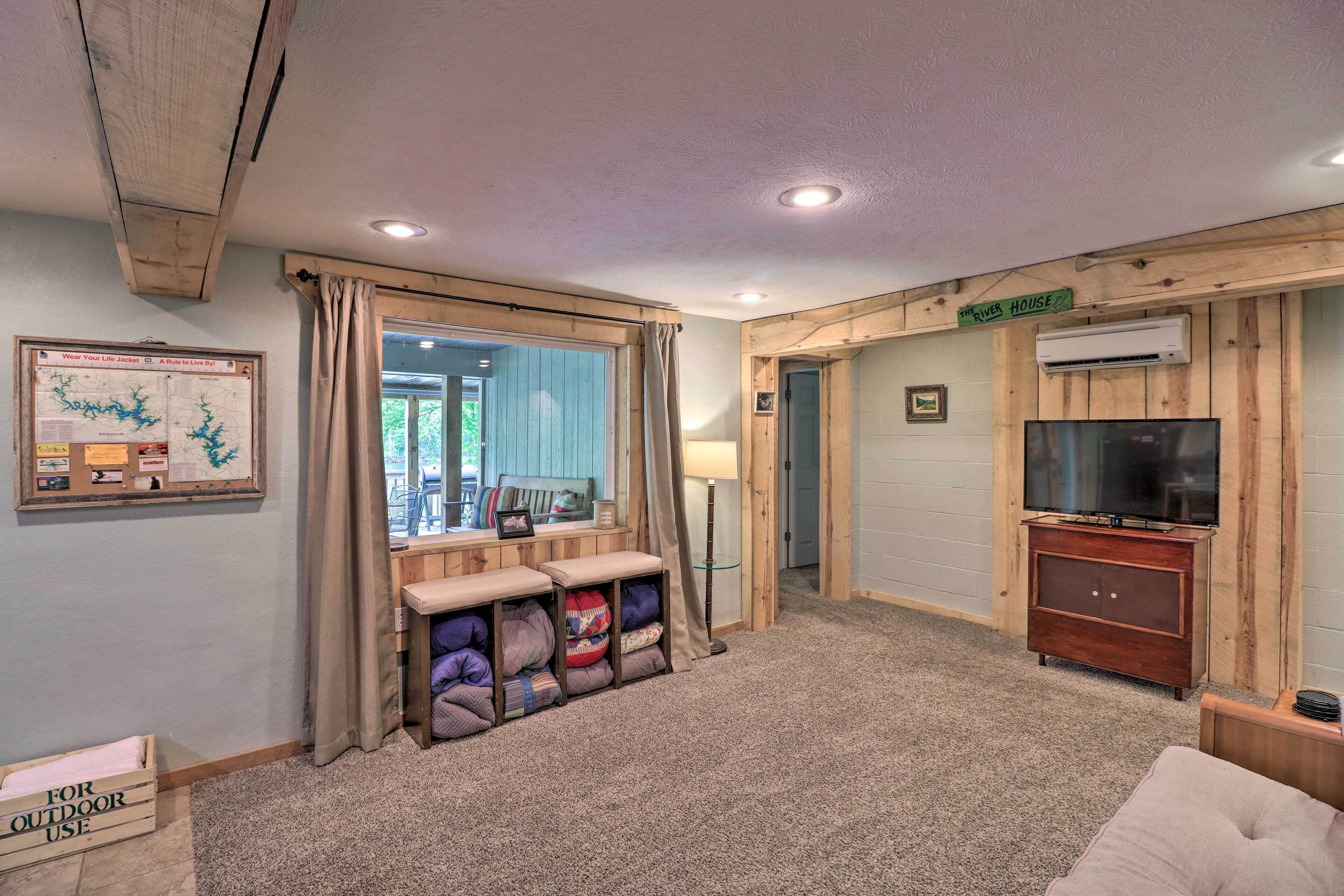 A cozy room with a large window, a television, a wooden cabinet, and a sign reading "River House."