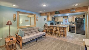 Una cocina compacta con muebles de madera, un refrigerador y una barra con taburetes.